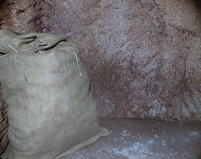Sac de toile de jute appuyé contre une paroi de roche poussiéreuse, salle La ruée vers l'or chez Time Lapse