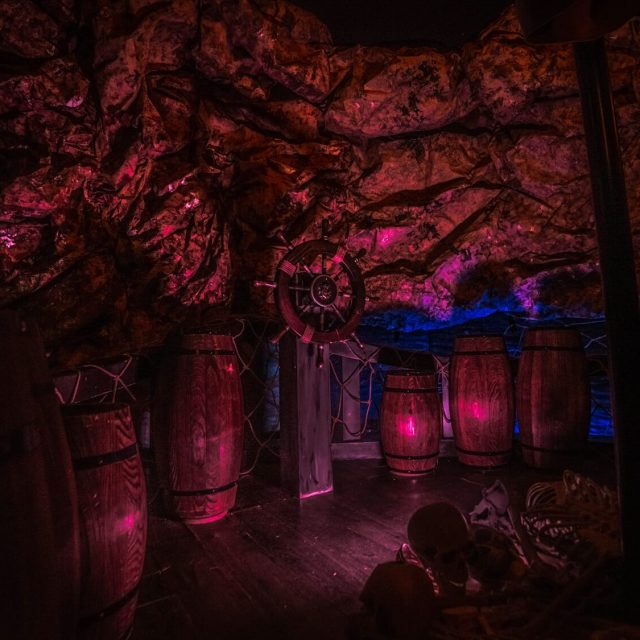 Décor de navire avec tonneau luminescent, roue de bateau et éclairages roses et bleus