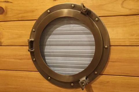 Hublot métallique sur paroi de bois dans la salle Le Naufrage
