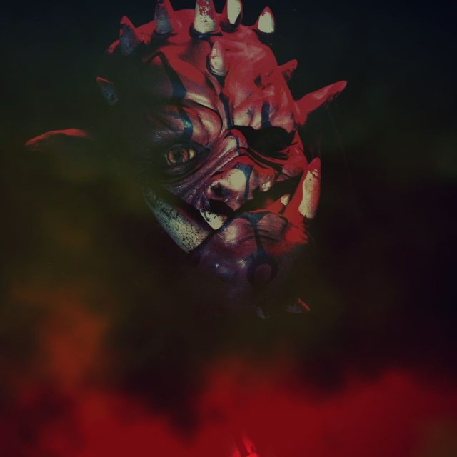 Masque rouge déformé aux traits menaçants dans l'obscurité à La Prison Gal'Roa