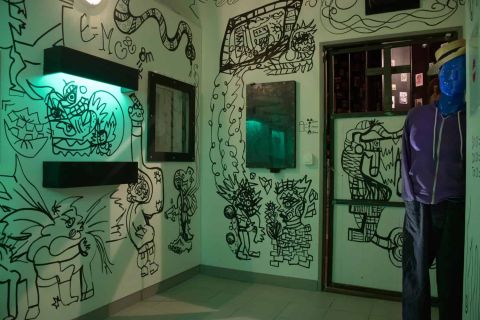 Murs blancs couverts de dessins noirs, mannequin à tête bleue, salle Le virus du professeur Zoltan chez Happy Hour à Paris
