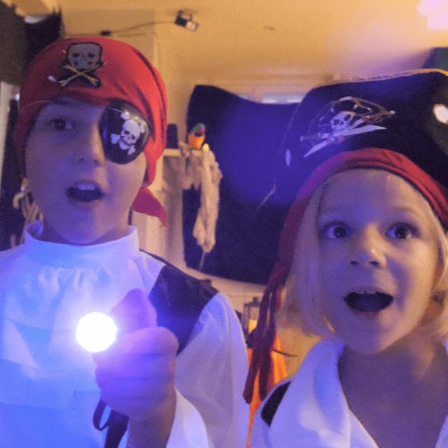 Deux enfants en costumes de pirates avec lampes torches, décor de bateau