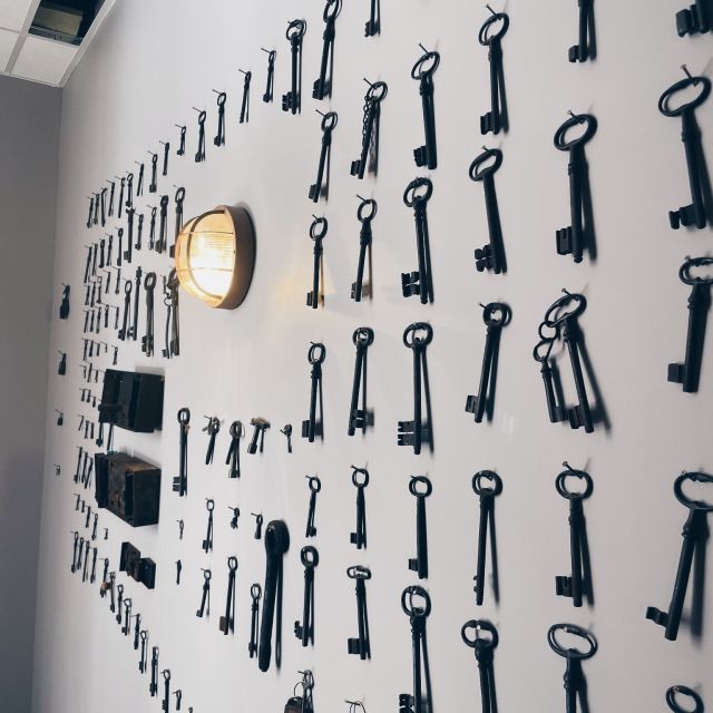 Mur blanc parsemé de clés noires de diverses tailles, lampe dorée au Château de Luc