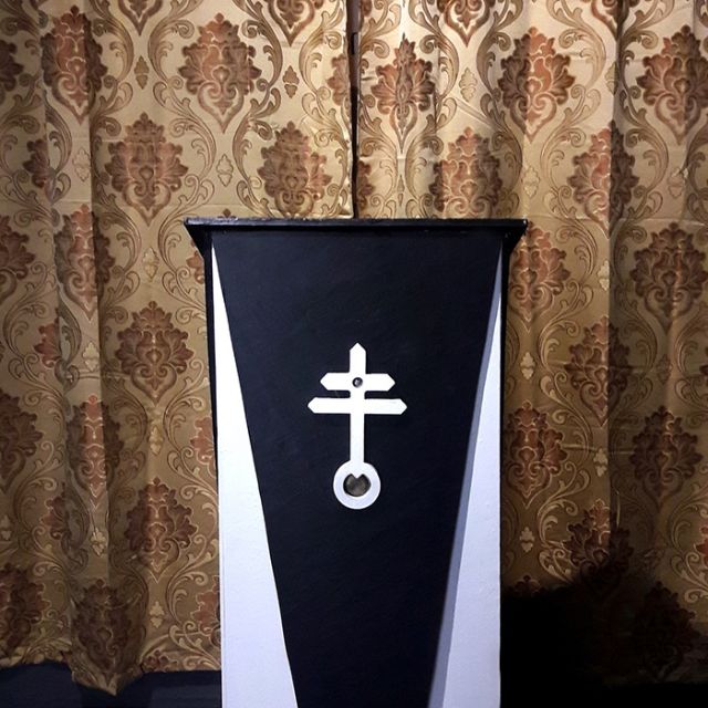 Cercueil noir orné d'une croix dans un décor baroque draché, L'intronisation à Fèves
