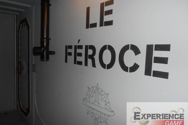 Mur blanc portant Le Féroce en lettres noires et conduit métallique, Experience Game à Saint-Lô