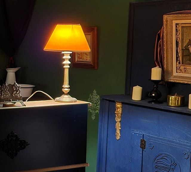 Commode bleue, lampe orange, bougies et portrait ancien encadré, salle Les sorciers de Calador chez Légendes Escape