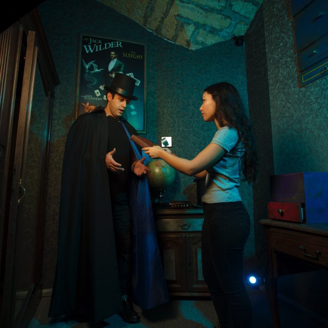 Deux joueurs interagissent dans un décor années 1920 aux murs turquoise chez Skryptic Escape Game à Montpellier