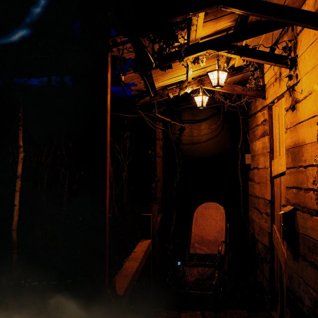 Ruelle d'un village de bois éclairée de lanternes dans la brume, salle La cabane dans les bois, Prisme Escape Game