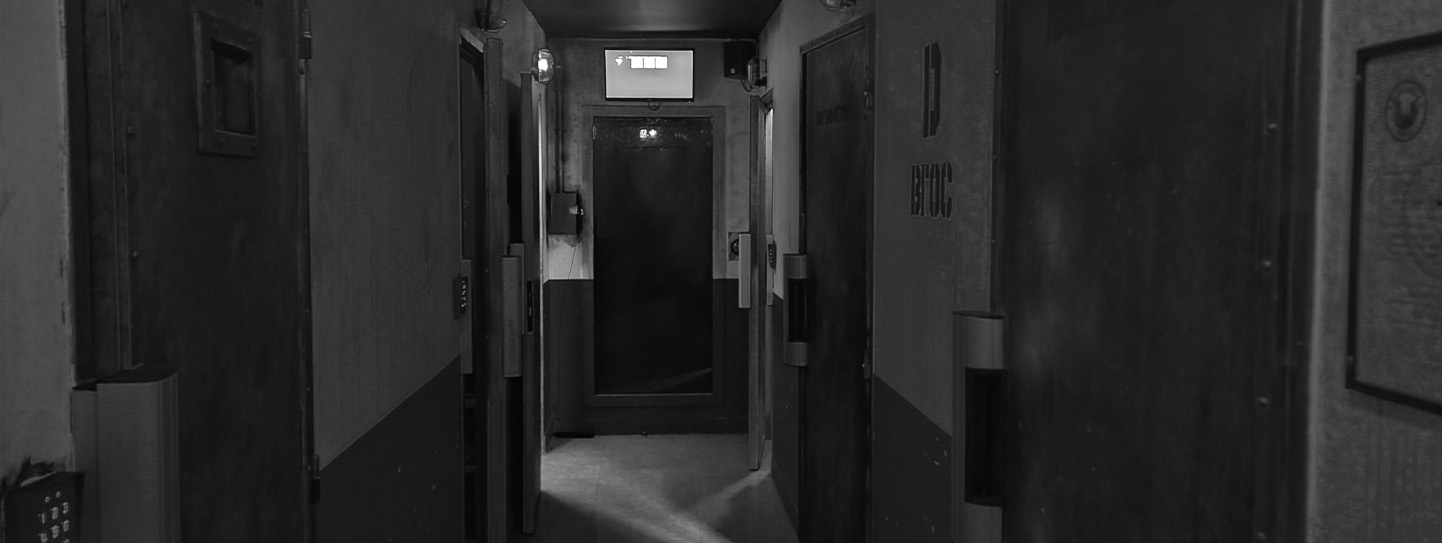 Couloir sombre d'une prison avec portes métalliques et affichage lumineux
